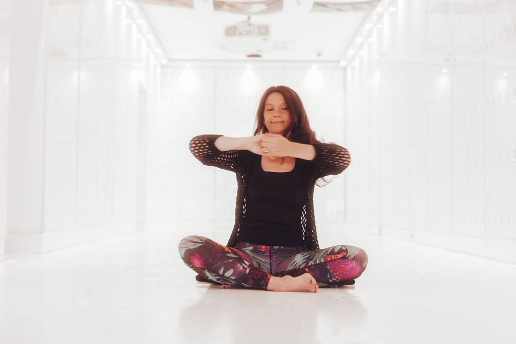 Nauči se dihalnih tehnik za boljše hormonsko ravnovesje. Ženska izvaja dihalne vaje hormonske joge v studiu.